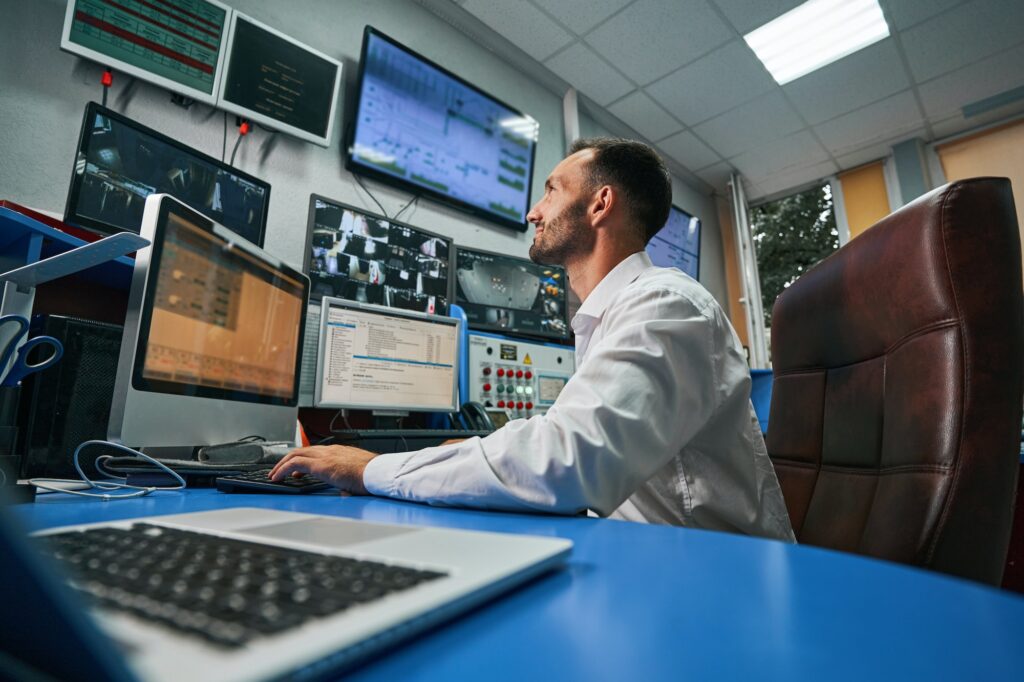Data center technician at computer watching camera image on screen