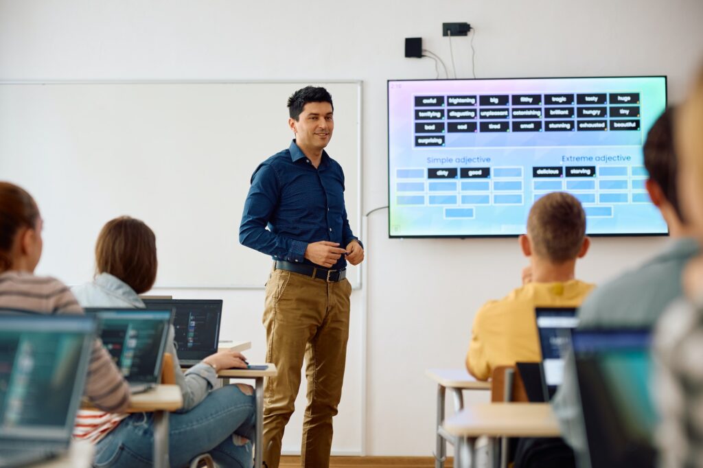 Happy computer science professor teaching students during a class in the classroom.